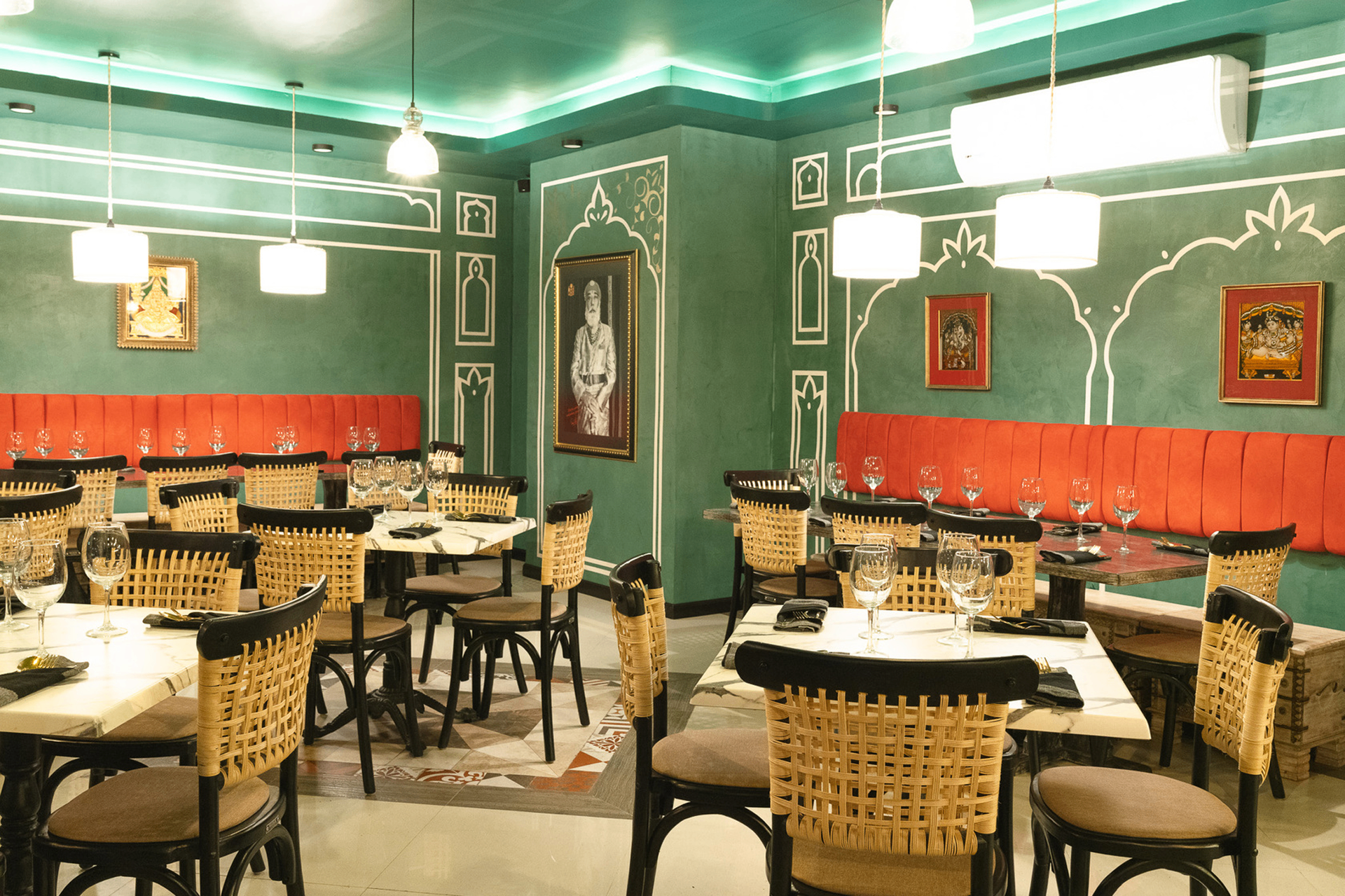 India Jones - Dining room with traditional Indian architectural elements, green walls, orange banquettes, and vintage Indian artwork