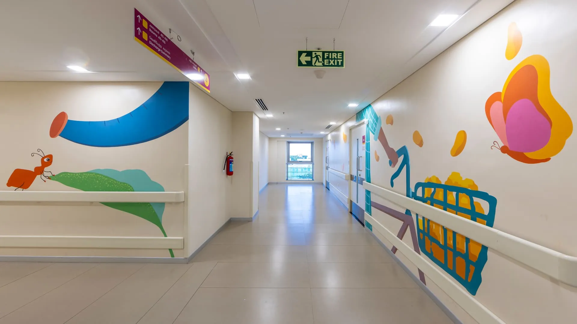 Kauvery Hospital - Corridor with ant and cycling storybook murals beside the fire exit